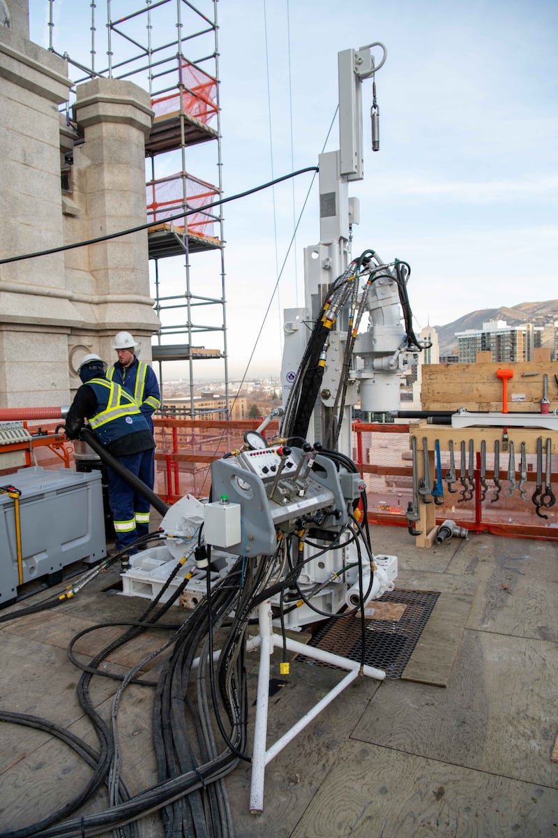 Workers use a drill on the roof of the Salt Lake Temple to drill inside tower and wall columns to prepare for tension cables.