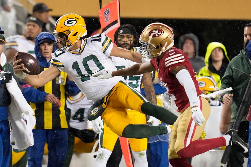 Green Bay Packers quarterback Jordan Love (10) leaps past San Francisco 49ers cornerback Deommodore Lenoir (2) during the first half of an NFL football NFC divisional playoff game Saturday, Jan. 20, 2024, in Santa Clara, Calif.