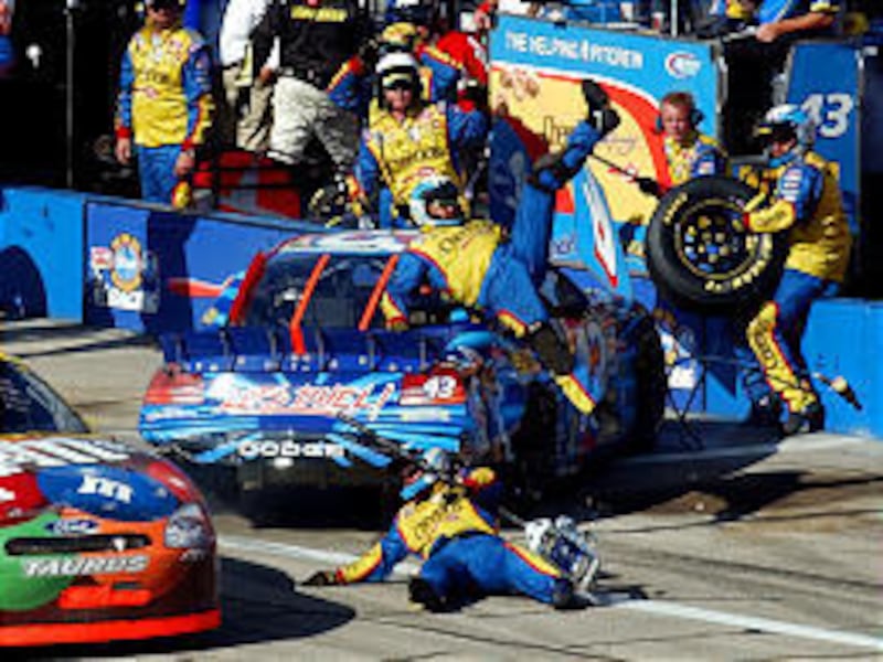 A member of Jeff Green's pit crew, center, goes flying through the air Sunday after Green's car was spun around by Elliott Sadler at Talladega.