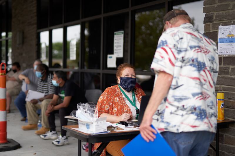 In this July 15, 2020, file photo, One-stop operator Vickie Gregorio with the Heartland Workforce Solutions talks to a jobseeker outside the workforce office in Omaha, Neb., as others seeking employment wait behind her.