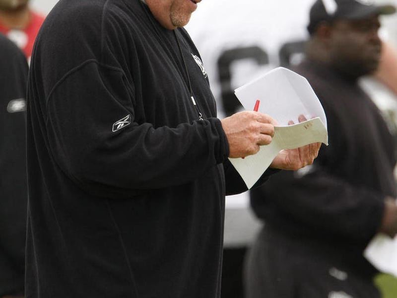 In this June 9, 2010, photo, then-Oakland Raiders coach Tom Cable goes over papers during organized team activities at the NFL football team's headquarters in Alameda, Calif. Cable has filed a grievance to recover $120,000 that the team fined him during t