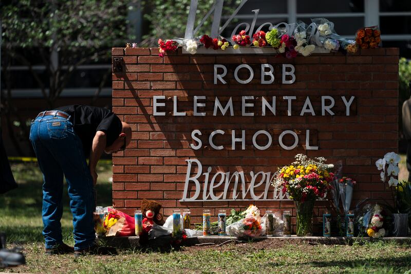A law enforcement personnel lights a candle outside of Robb Elementary School in Uvalde, Texas.