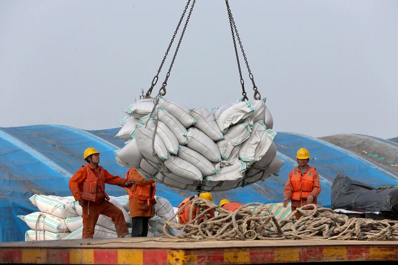 In this March 22, 2018, photo, workers load imported soybeans at a port in Nantong in east China's Jiangsu province. China on Wednesday, April 4, 2018 vowed to take measures of the "same strength" in response to a proposed U.S. tariff hike on $50 billion