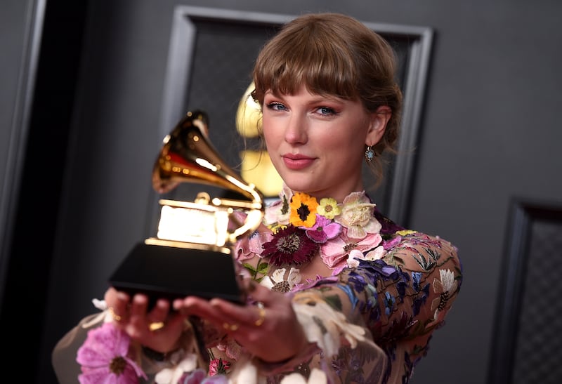 Taylor Swift poses in the press room with the award for album of the year for “Folklore” at the 63rd annual Grammy Awards at the Los Angeles Convention Center on Sunday, March 14, 2021.