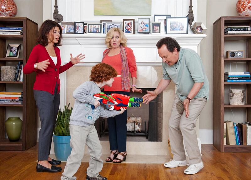 Artie (Billy Crystal) reacts to grandson Barker's (Kyle Harrison Breitkopf) water-rifle shenanigans, as mom Alice (Marisa Tomei) and grandma Diane (Bette Midler) look on.