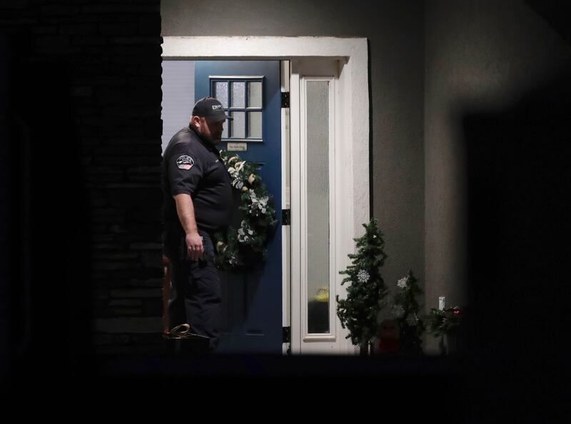 A law enforcement official stands at the front door of the Enoch, Iron County, home where eight family members were found shot to death Wednesday, Jan. 4, 2023.