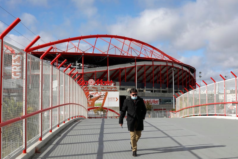 A man wearing a face mask walks outside the SL Benfica stadium in Lisbon.