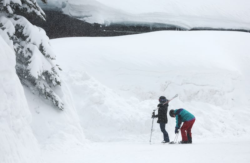 Skiers walk below towering snowbanks at Solitude in Big Cottonwood Canyon on Tuesday, April 4, 2023.