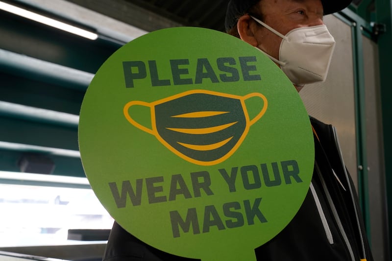 A stadium worker holds up a sign for people to wear face masks.