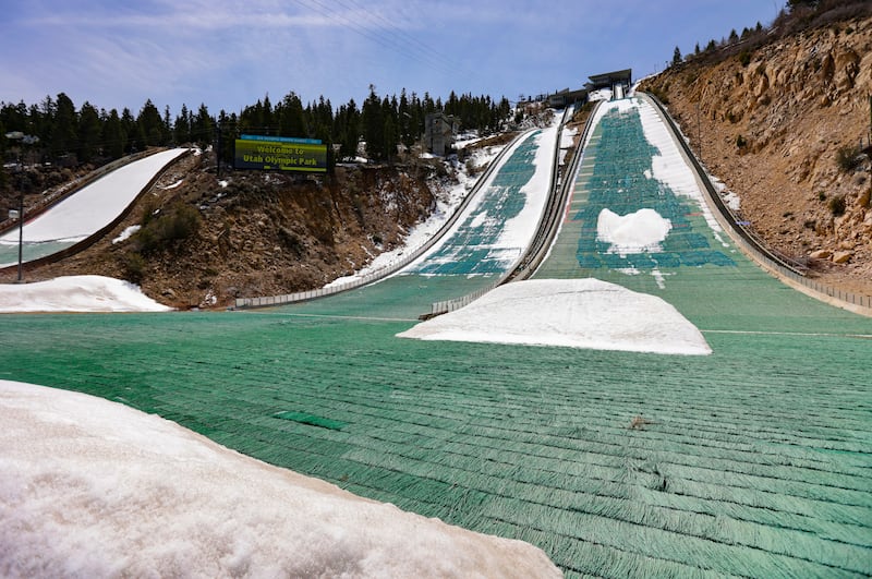 Snow on the K10/20 ski jump melts revealing the grass underneath at the Utah Olympic Park in Park City.