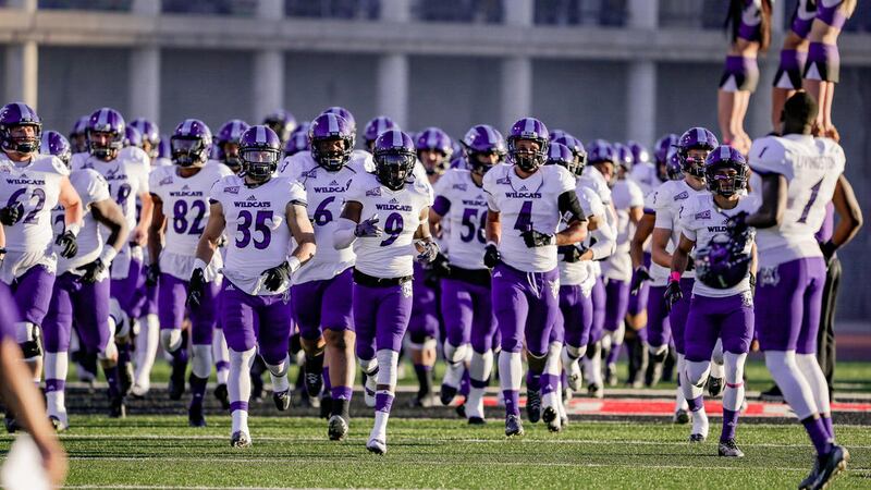Weber State football players run onto the field. The Wildcats will compete in the FCS Playoffs for the first time since 2009.