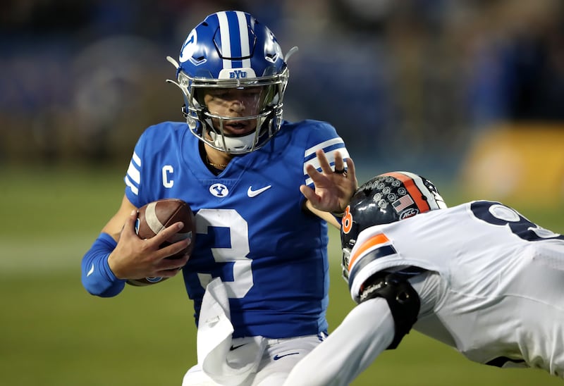 Brigham Young Cougars quarterback Jaren Hall. wearing blue, stiff-arms Virginia Cavaliers cornerback Darrius Bratton
