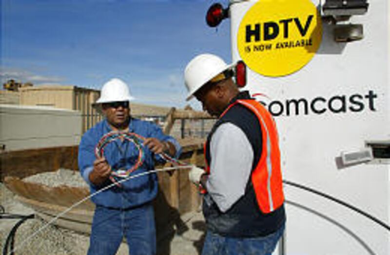 Comcast technicians Lyndon Lauhingoa and Rodney Bell help slice cable as it is installed throughout Draper.