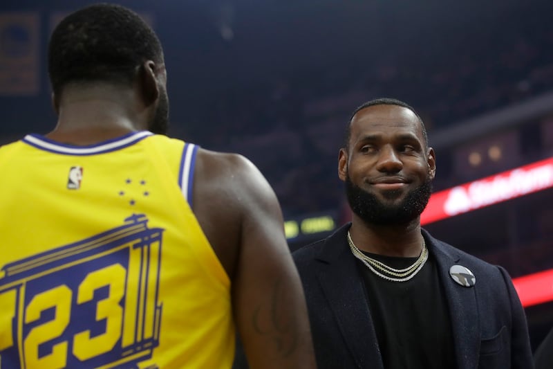 Los Angeles Lakers forward LeBron James, right, smiles while talking with Golden State Warriors forward Draymond Green during the first half of an NBA basketball game