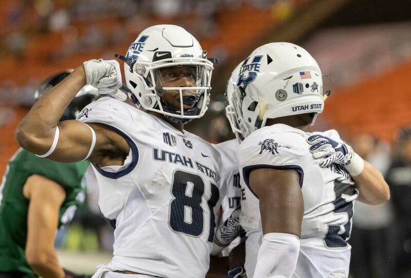 FILE - In this Saturday, Nov. 3, 2018 file photo, Utah State wide receiver Savon Scarver (81) celebrates a touchdown run by his teammate running back Darwin Thompson (5) in the second half of an NCAA college football game against Hawaii in Honolulu. The h
