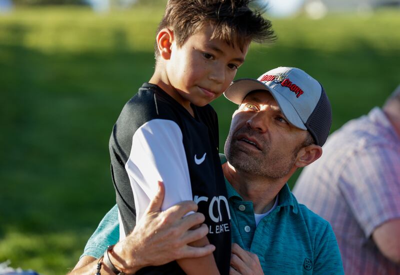 Richard Nuffer holds his son, Lynx, 8, during halftime as his team, Utah Glory, plays the Cottonwood Football Club.
