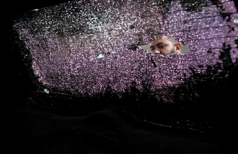 A man looks through a broken window of a car damaged by shelling in Stepanakert, the self-proclaimed Republic of Nagorno-Karabakh, Azerbaijan, Tuesday, Sept. 29, 2020. Armenian and Azerbaijani forces accused each other of attacks on their territory Tuesday, as fighting over the separatist region of Nagorno-Karabakh continued for a third straight day following the reigniting of a decades-old conflict.