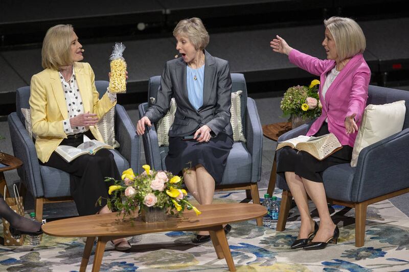 Sister Jean B. Bingham, Relief Society General President; holds a bag of popcorn before giving it to Sister Joy D. Jones, Primary General President, who reacts to the gift as Sister Bonnie H. Cordon, Young Women General President; reacts aswell at a "Sist