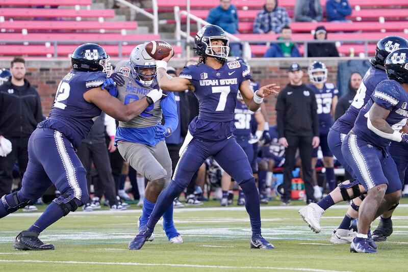 Utah State quarterback Bishop Davenport (wearing blue) throws the ball