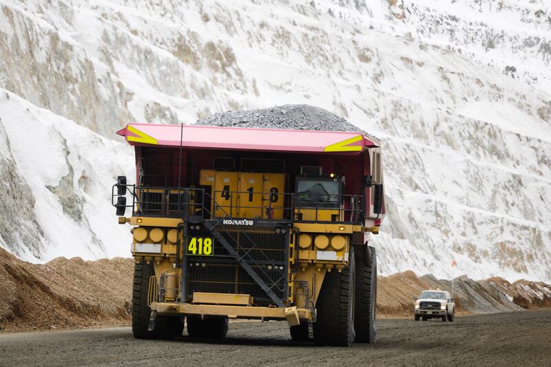 A haul truck looms over a crew truck with a full load of copper ore waste at the Rio Tinto Kennecott Copper Mine.