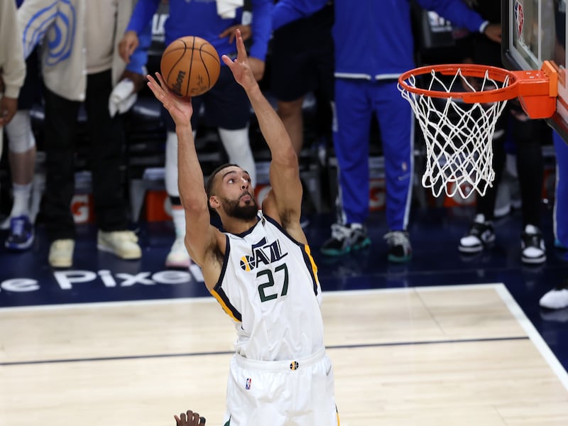 Utah Jazz center Rudy Gobert (27) catches an alley-oop pass from teammate Donovan Mitchell (45) on his way in for a dunk.