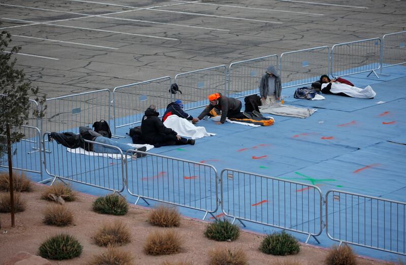 People rest at a makeshift camp for the homeless Saturday, March 28, 2020, in Las Vegas. Officials opened part of a city parking lot as a makeshift homeless shelter after a local shelter closed when a man staying there tested positive for the coronavirus. (AP Photo/John Locher)