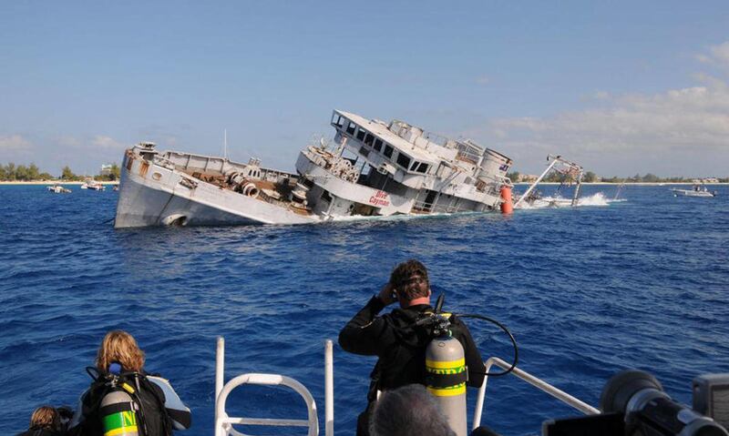 In this photo released by the Cayman Islands Department of Tourism, divers watch the sinking of the USS Kittiwake, a 1945-vintage submarine rescue ship, off the Cayman Islands, Wednesday Jan. 5, 2011. Contractors flooded the decommissioned U.S. Navy ship