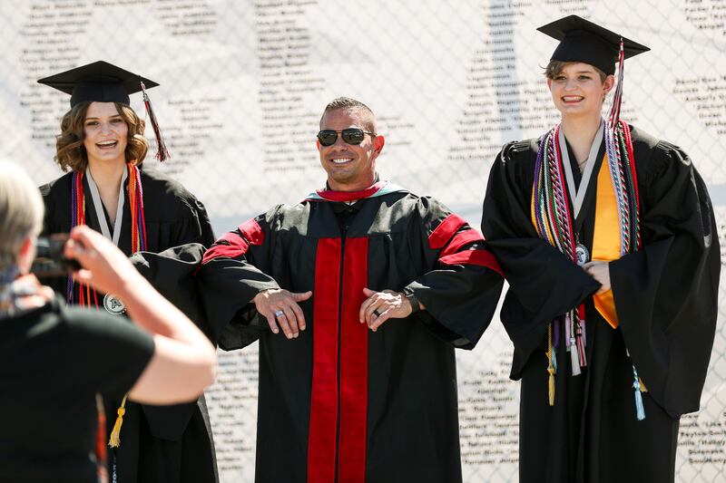 Principal Brian McGill elbow-bumps twin sisters Isabel and Abigail Hales during a drive-through graduation ceremony at Alta High School in 2020.