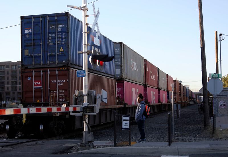 John Kamai waits for a train to pass before crossing the tracks in Salt Lake City on Tuesday, Sept. 25, 2018.