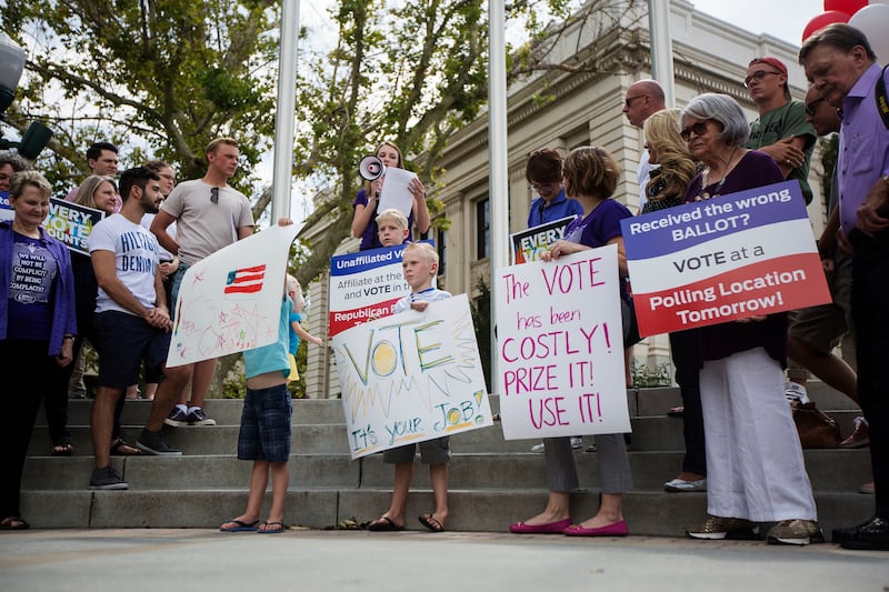 Megan Seawright, center, uses a megaphone to discuss the importance of voting during a rally outside the historic Utah County Courthouse in Provo on Monday, August 14, 2017. During the rally, sponsored by Mormon Women for Ethical Government and other conc