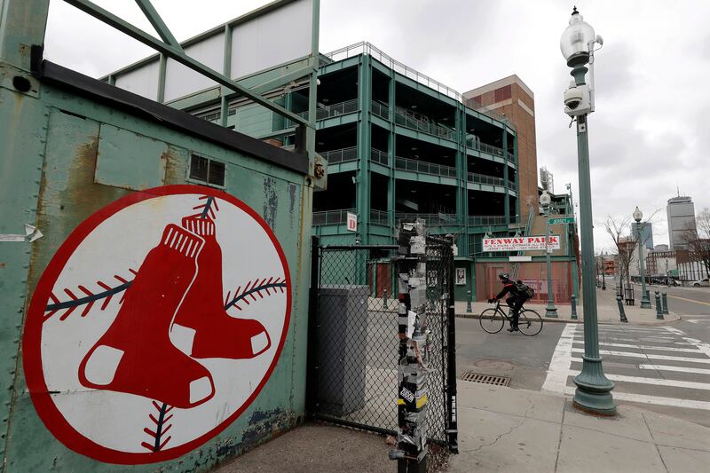 A cyclist rides past Fenway Park baseball park, March 25, 2020, in Boston. There will be empty ballparks on what was supposed to be Major League Baseball’s opening day, with the start of the Major League Baseball regular season indefinitely on hold because of the coronavirus pandemic. (AP Photo/Steven Senne)