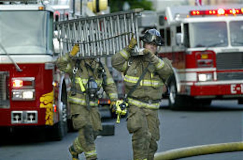 Firefighters carry a ladder to a building on 100 South in Salt Lake that caught fire on Monday.