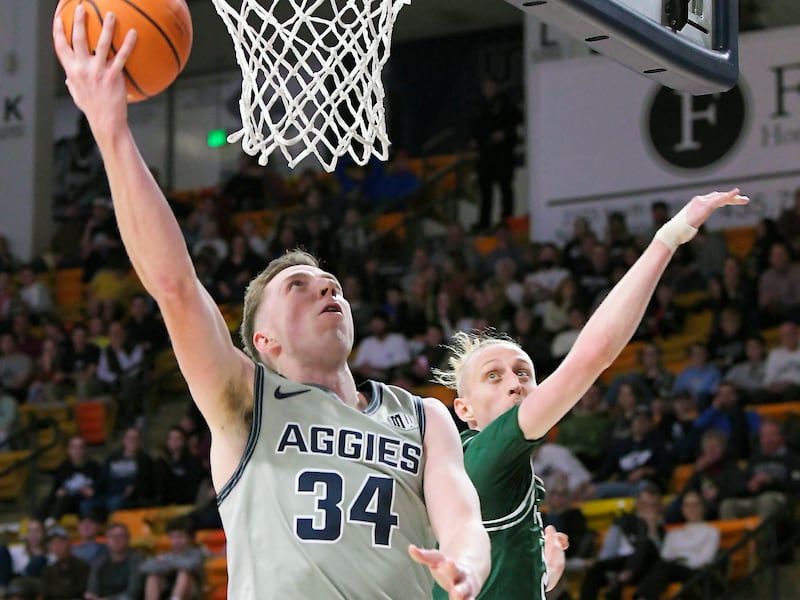 Utah State forward Justin Bean, wearing grey, takes a shot as Portland State guard Ian Burke defends