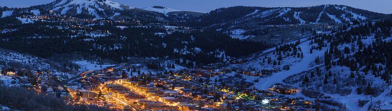 Dusk View of Park City Glowing. Scenic village from above with cool blue dusk light and glowing warm lights. Dusk View of Park City Glowing
