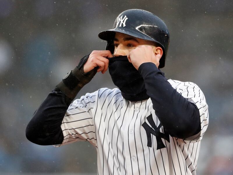 New York Yankees’ Tyler Wade adjusts his neck gaiter over his face during the second inning of an opening day baseball game against the Tampa Bay Rays at Yankee Stadium in New York, Tuesday, April 3, 2018.