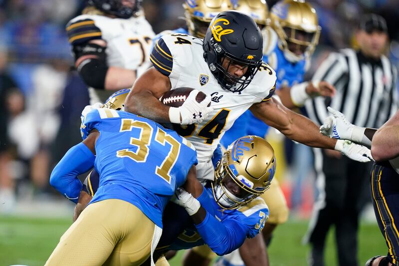 California’s Christopher Brooks is stopped by UCLA defenders Saturday, Nov. 27, 2021, in Pasadena, Calif.