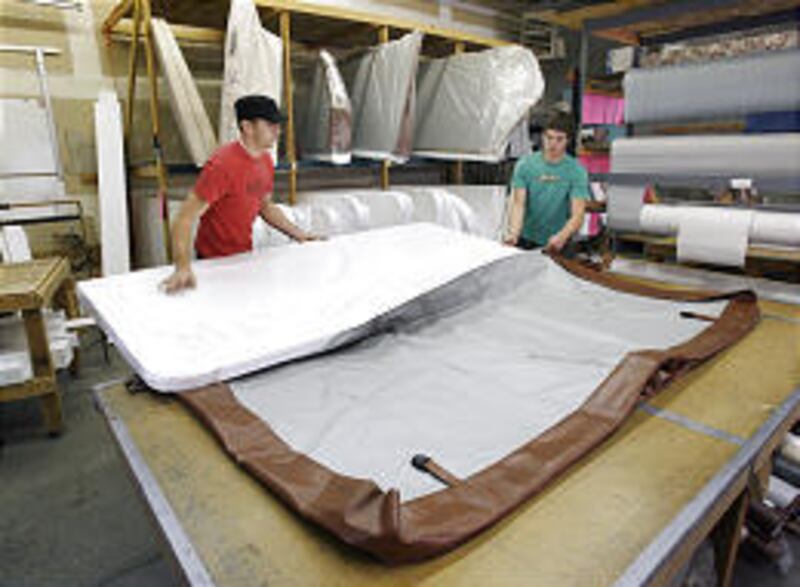 Robbie Warren and Kalen Restad slide foam into a vinyl cover for a spa at Cedar Mountain Manufacturing in Springville.