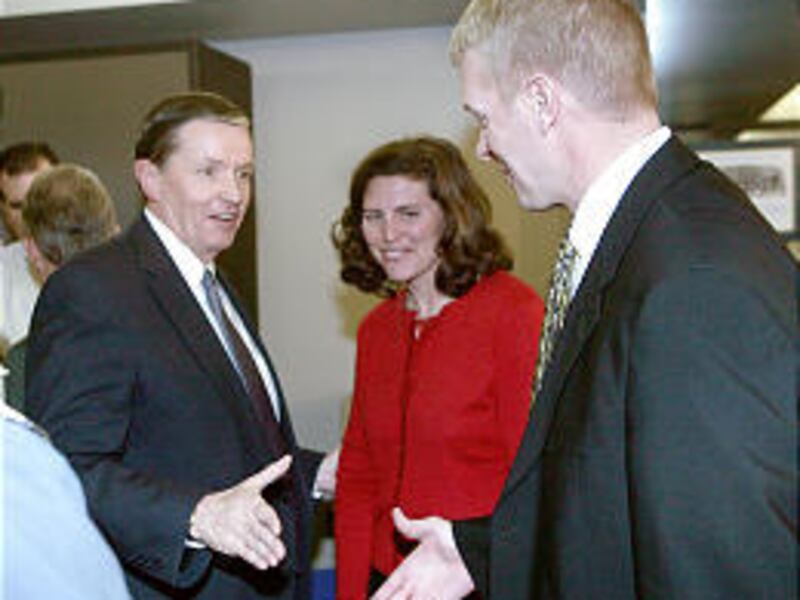 BYU grid coach Bronco Mendenhall, right, shakes hands with BYU President Cecil Samuelson, while Mendenhall's wife, Holly, watches.