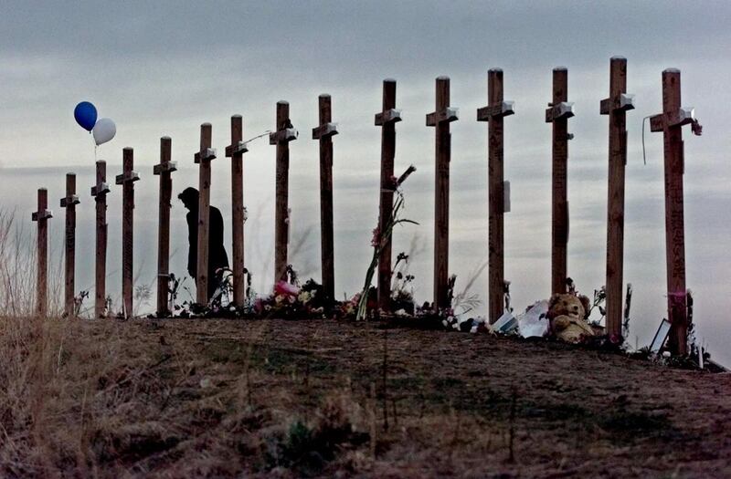 FILE - In this April 28, 1999, file photo, a woman stands among 15 crosses posted on a hill above Columbine High School in Littleton, Colo., in remembrance of the 15 people who died during a school shooting on April 20, 1999. The mother of Columbine High