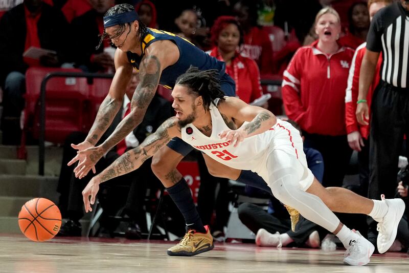 Houston guard Emanuel Sharp and West Virginia guard RaeQuan Battle chase the ball during a game.