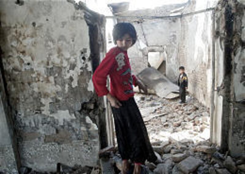 Children search the charred ruins of a police station Sunday that was burned during rioting in the Uzbek border town of Korasuv.