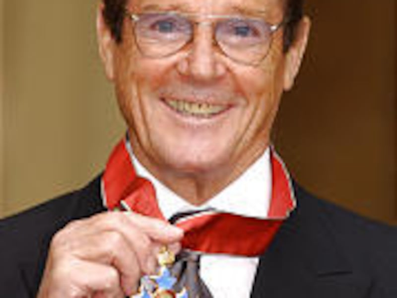 Sir Roger Moore displays his medal.