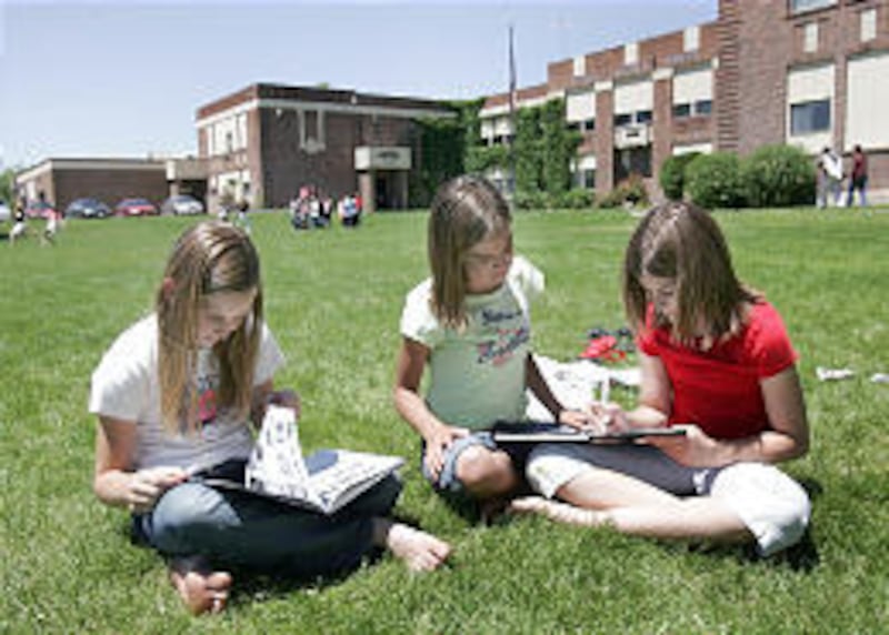 Katie Williams, left, Jaelynn Hemingway and Melissa Case, seventh-graders at Farrer Middle School, look at their yearbooks in front of the school.