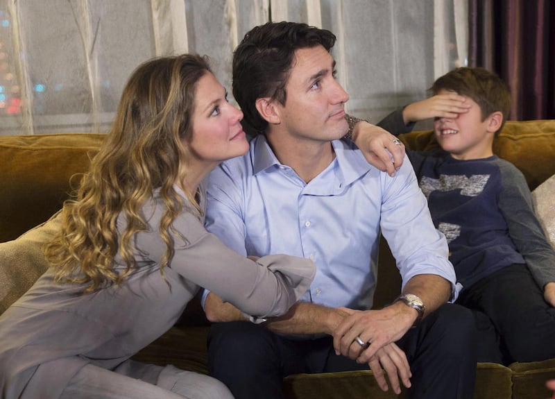 Xavier Trudeau, right, covers his eyes as Liberal leader Justin Trudeau watches the election results with his wife Sophie Gregoire at a hotel in downtown Montreal on Monday, Oct. 19, 2015.