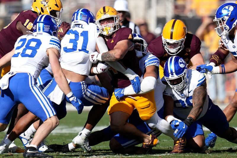 Arizona State running back Cam Skattebo, center, gets stopped by BYU cornerback Kevin Doe (31), and other BYU defenders, during game Saturday, Nov. 23, 2024, in Tempe, Ariz.