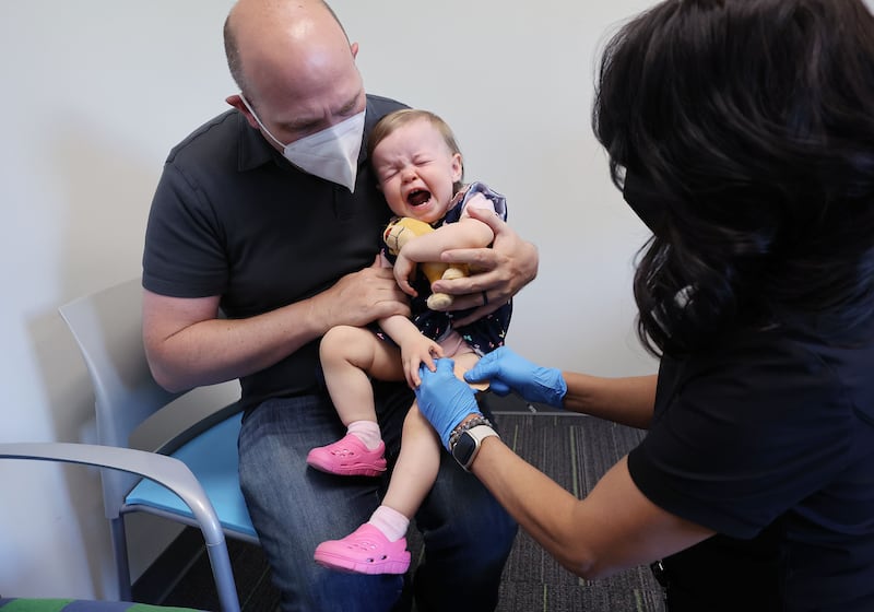 Lennox Rupp gets her COVID-19 vaccine as her father, Michael Rupp, holds her at the Salt Lake Public Health Center.