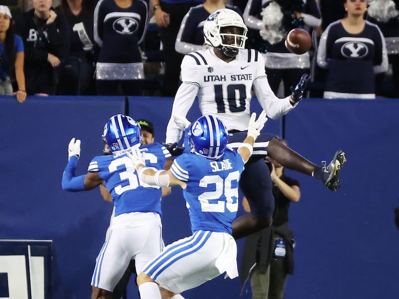 Utah State Aggies wide receiver Justin McGriff (10) and Brigham Young Cougars defensive back Ethan Slade (26) compete for the ball