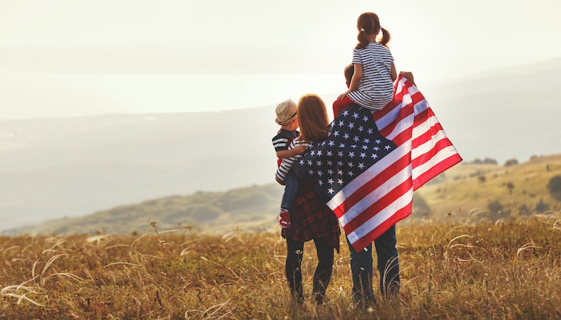 happy family with the flag of america USA at sunset outdoors