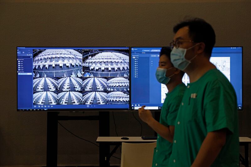 Medical workers walk past a TV screen for monitoring the temporary field hospital set up at Asia World Expo in Hong Kong, Saturday, Aug. 1, 2020.
