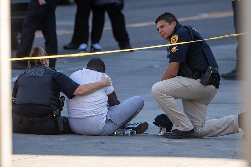 Officers console a man inside of a crime scene on 100 South, where a shooting left one dead in Salt Lake City.